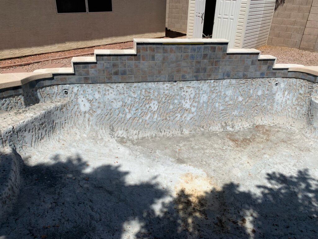 An empty pool during renovation, showing new tile work on the waterfall feature by East Mesa Pools, LLC in Mesa, AZ.