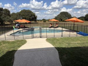A professional pool safety fence installation with a black mesh barrier by Lone Star Pool Fence in Houston, TX.