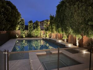A swimming pool and spa area with elegant landscape and underwater lighting, installed by GL3 Luxury Lighting in Anaheim, CA.