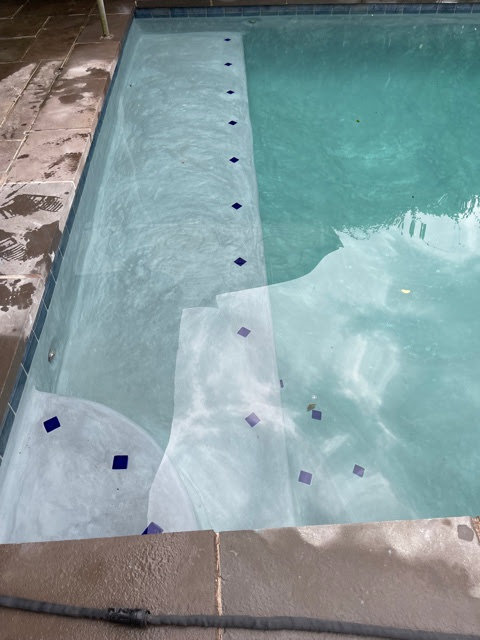Swimming pool steps with a light plaster finish and decorative blue square tiles, installed by I10 Pool Plastering LLC in Kenner, LA.