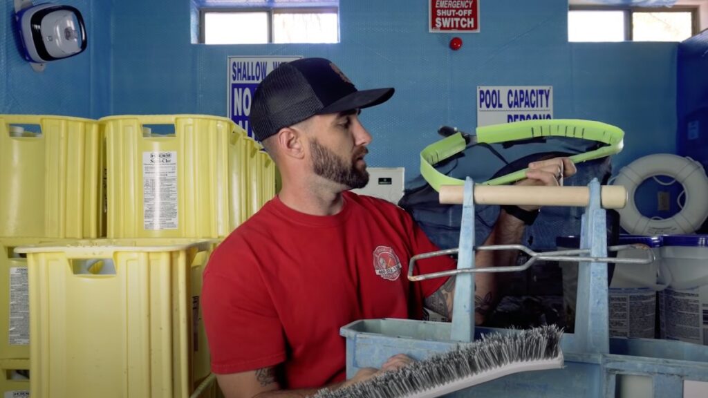 A pool technician holding various cleaning tools, including a brush and skimmer pole, for Pool Rescuers LLC in Gilbert, AZ.