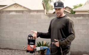 A pool technician holding a drain pump and hose, performing a service for Pool Rescuers LLC in Gilbert, AZ.