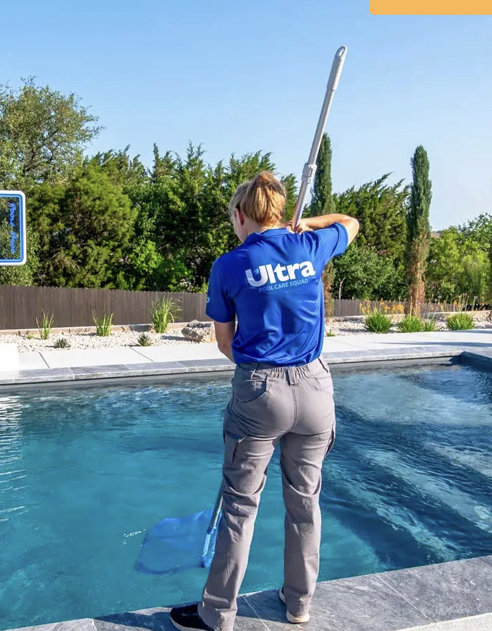 A pool technician skimming leaves from a pool with a net for Ultra Pool Care Squad of East Chattanooga, TN.