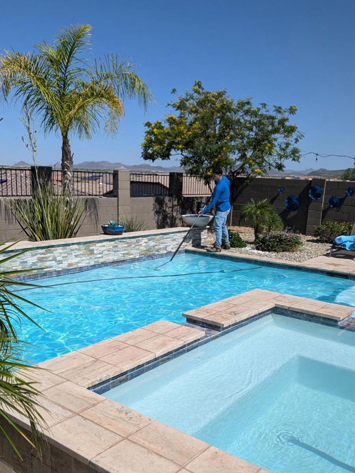 A pool technician vacuuming a residential swimming pool for Parkinson Pools in Peoria, AZ