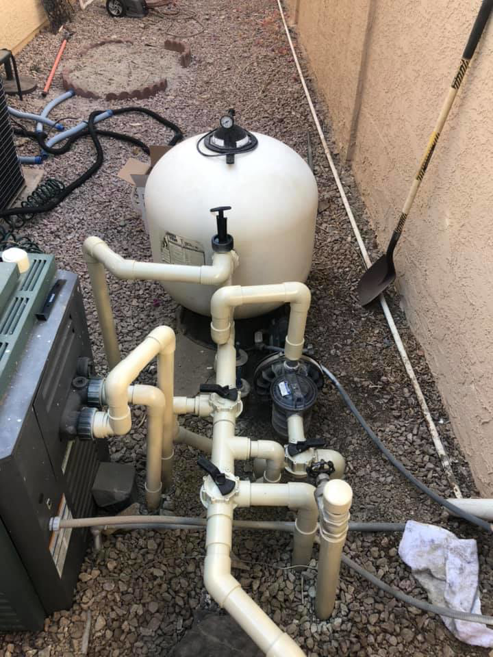 A pool technician working on the plumbing and filter system for BEHR POOLS Service & Repairs in Glendale, AZ