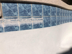 Close-up of pool tiles with heavy scale buildup before cleaning by Surprise Pool & Spa in Surprise, AZ
