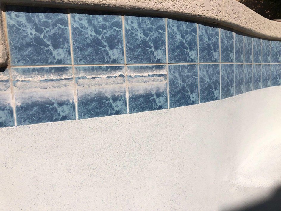 Close-up of pool tiles with heavy scale buildup before cleaning by Surprise Pool & Spa in Surprise, AZ