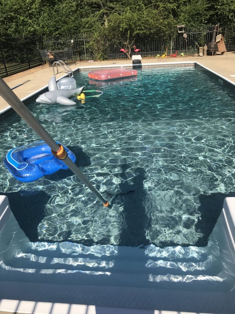 A pool vacuum actively cleaning the bottom of a swimming pool by Four Seasons Pool Services in Shreveport, LA.