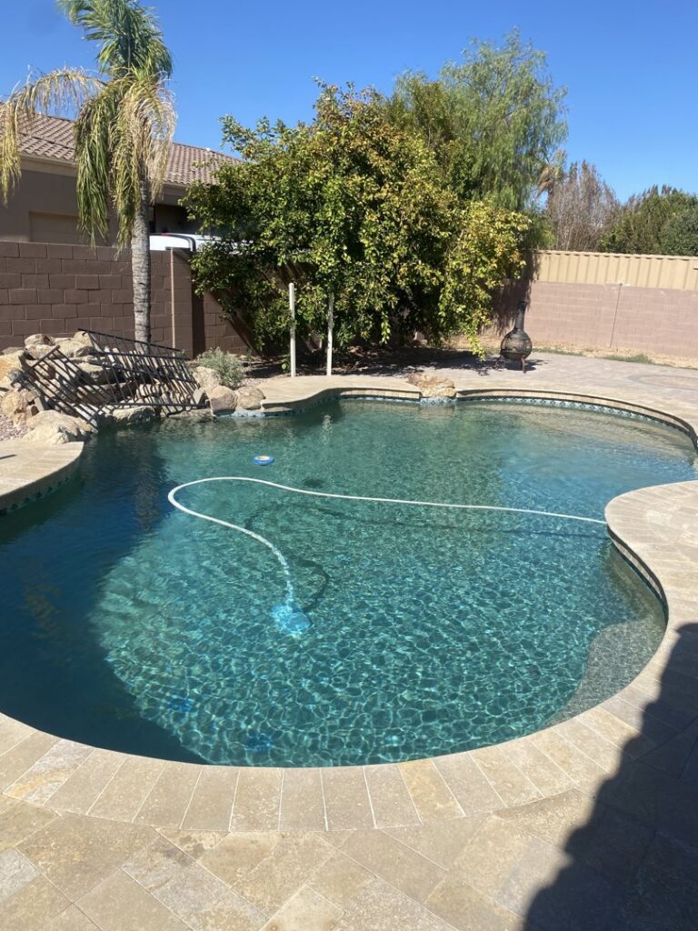 A pool vacuum cleaning a sparkling blue swimming pool, demonstrating service by BEHR POOLS Service & Repairs in Glendale, AZ