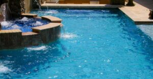 A close-up of a swimming pool with an integrated spa and water features by Blue Magic Pools and More Inc. in Gilbert, AZ.
