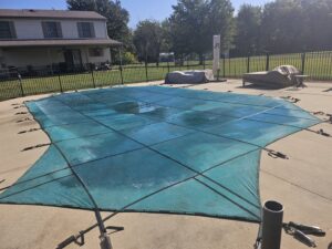 An inground pool securely covered with a green mesh safety cover, demonstrating pool closing services by Westside Pools in Owensboro, KY.