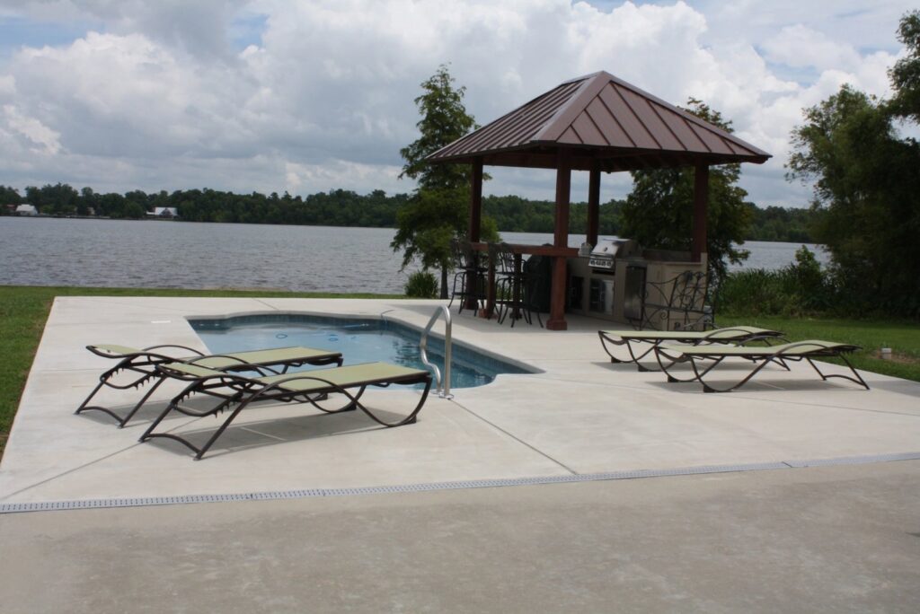 A custom inground pool with a spa and outdoor kitchen overlooking a lake by Central Pools, Inc. in Baton Rouge, LA.