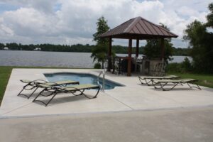 A custom inground pool with a spa and outdoor kitchen overlooking a lake by Central Pools, Inc. in Baton Rouge, LA.