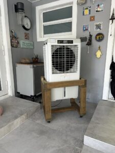 A portable evaporative cooler on a wooden stand providing indoor cooling by Cajun Kooling in Broussard, LA