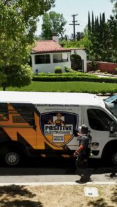 A Positive Electricians branded van with a worker at a residential job site in Van Nuys, CA.