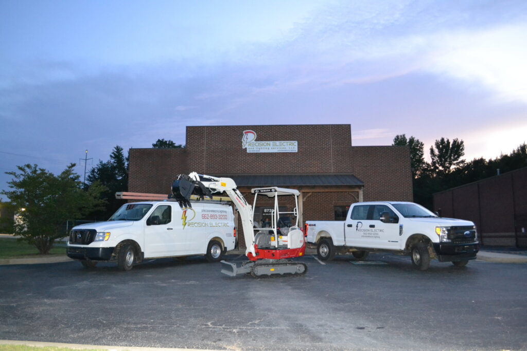 The fleet of Precision Electric and Lighting Services, LLC, including a work van, truck, and excavator, ready for electrical projects in Olive Branch, MS.