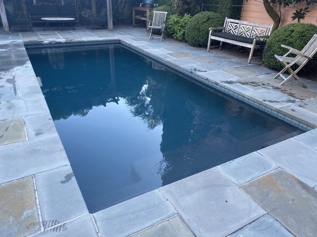 A pristine dark-bottomed rectangular swimming pool, expertly cleaned by Pool King in Southhold, NY.
