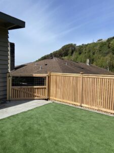 A wooden privacy fence with a gate featuring a wire mesh top section by Helmco Fences in Seattle, WA.