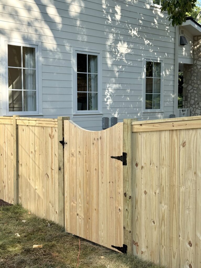 A privacy wooden fence and gate installed next to a white house by Heron Building Co in Franklin, TN.