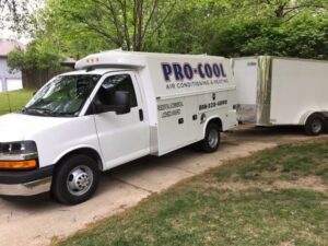 A Pro-Cool Air Conditioning & Heating service truck and trailer parked in a residential driveway in Blue Springs, MO.