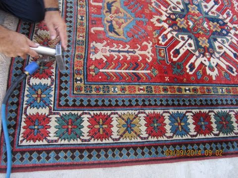 A professional cleaning an intricate red area rug with a specialized tool by My Dad's Floor and Upholstery Cleaning in Sacramento, CA.
