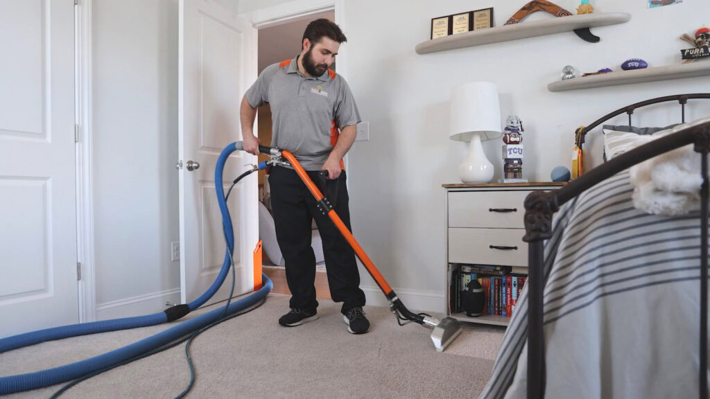 A professional technician performing carpet cleaning in a bedroom with a cleaning wand for Carpet & Rug Cleaning in Mount Pleasant, SC.
