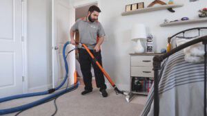 A professional technician performing carpet cleaning in a bedroom with a cleaning wand for Carpet & Rug Cleaning in Mount Pleasant, SC.