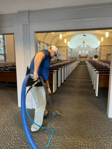 A professional technician cleaning carpet in a church with specialized equipment by The Steam Master Inc. in Fort Wayne, IN.