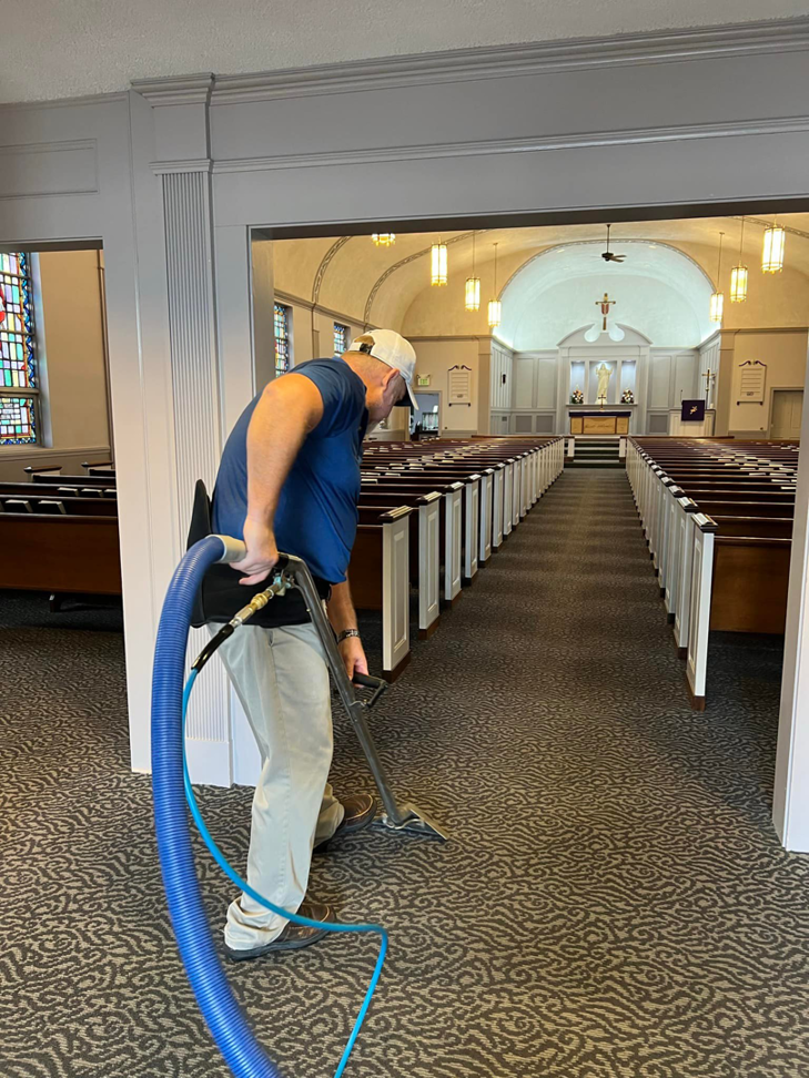 A professional technician cleaning carpet in a church with specialized equipment by The Steam Master Inc. in Fort Wayne, IN.