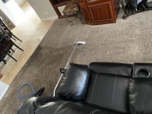 Professional carpet cleaning equipment, including a wand and hose, in a residential living room by Orozco's Janitorial Services LLC in Escondido, CA.