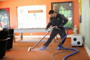 A Dirt Busters, Inc. technician performing professional carpet cleaning with a steam wand in Anaheim, CA.