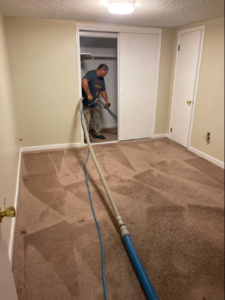 A professional performing deep carpet cleaning in a residential room for Master Green Cleaning in Overland Park, KS.