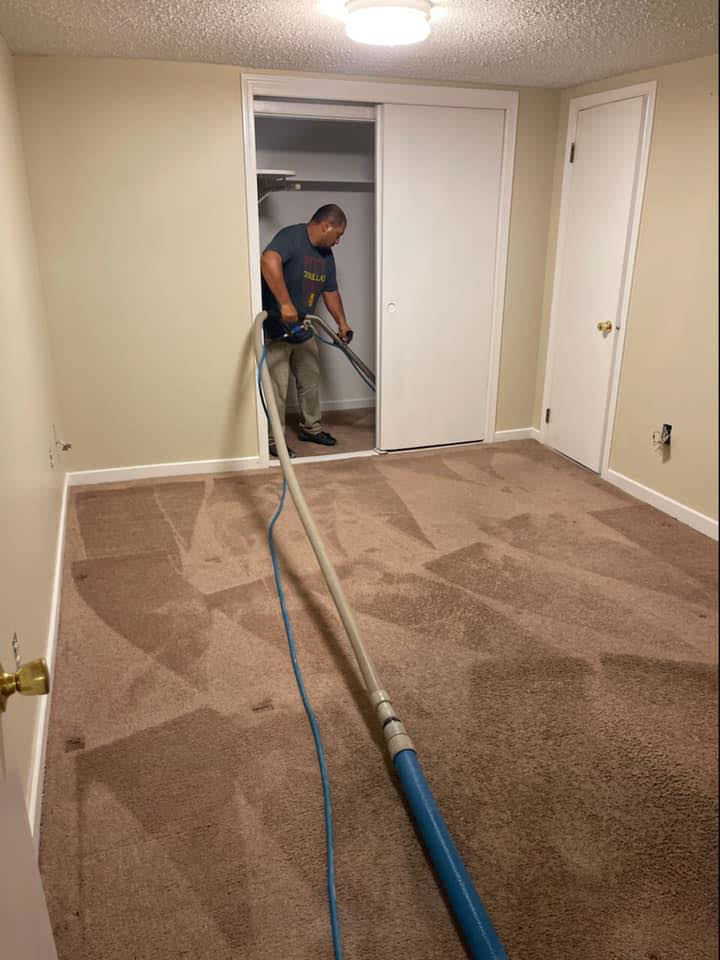 A professional performing deep carpet cleaning in a residential room for Master Green Cleaning in Overland Park, KS.