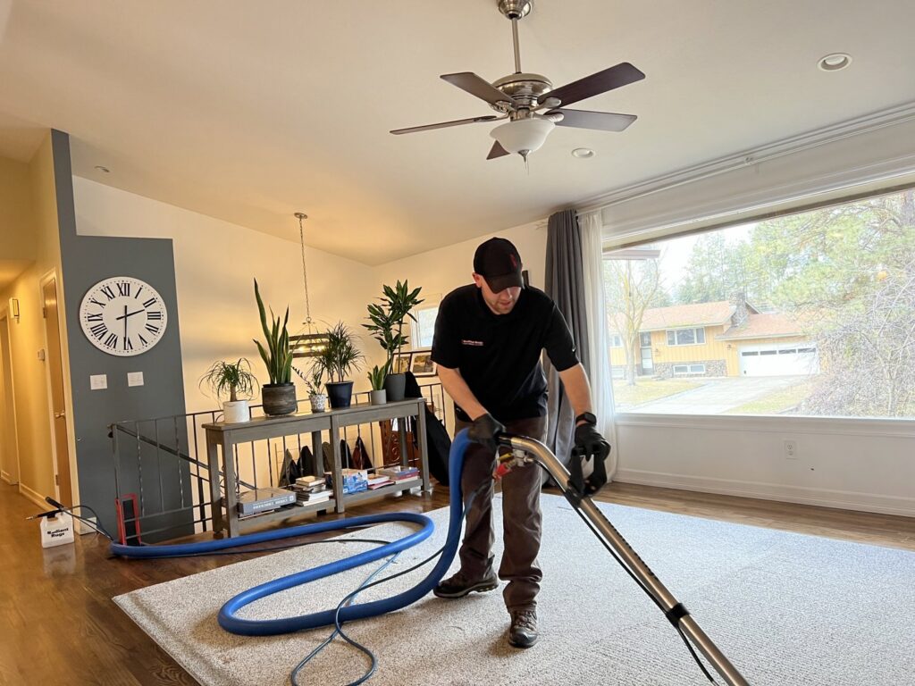 A professional from Radiant Rugs Carpet Cleaning performing carpet cleaning in a living room in Spokane, WA.
