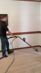 A technician performing professional carpet cleaning with a wand for Regional Carpet Care in Garner, NC.