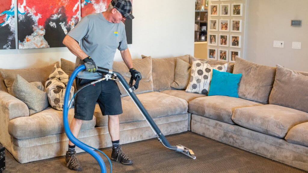 A professional cleaning a carpet with a specialized wand for Renew Cleaning Services in Scottsdale, AZ.