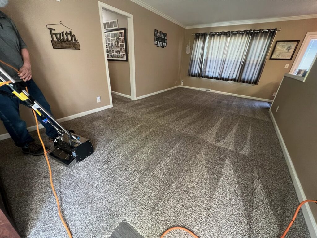A professional operating a carpet cleaning machine, actively cleaning a carpet for Dewdrop Carpet Cleaning in Kansas City, MO.