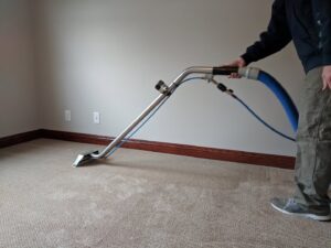 A professional performing carpet cleaning with a wand, showing clean lines, by Premium Carpet Care in Lincoln, NE.