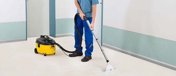 A professional performing carpet cleaning with an extractor machine for White Glove Professional Cleaning Inc. in Jackson, WY.