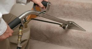 A professional cleaning technician using a specialized tool to clean carpeted stairs for Steam Giant in Raleigh, NC.