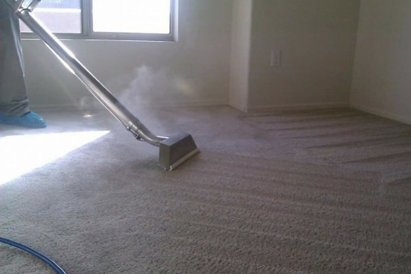 A professional using a steam cleaning wand to clean a carpet, showcasing Mid State Contract Cleaners in Nashville, TN.