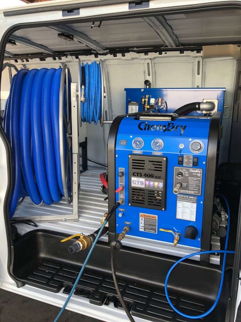 A large professional carpet and upholstery cleaning machine and hoses inside a Chem-Dry Nona service van in Orlando, FL.