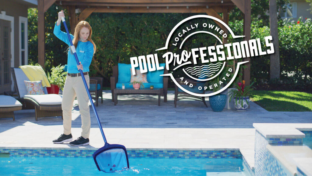 A professional pool cleaner skimming a swimming pool as part of a service from Pinch A Penny Pool Patio Spa in Mobile, AL.