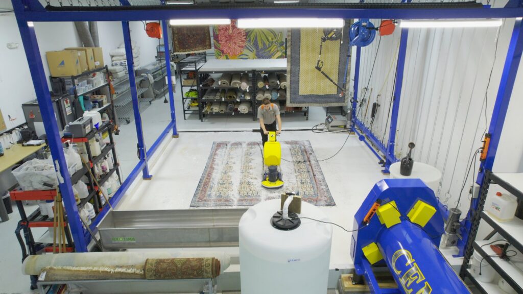 An overhead view of a professional rug cleaning facility, showing a technician cleaning a rug with specialized equipment at Carpet & Rug Cleaning in Mount Pleasant, SC.