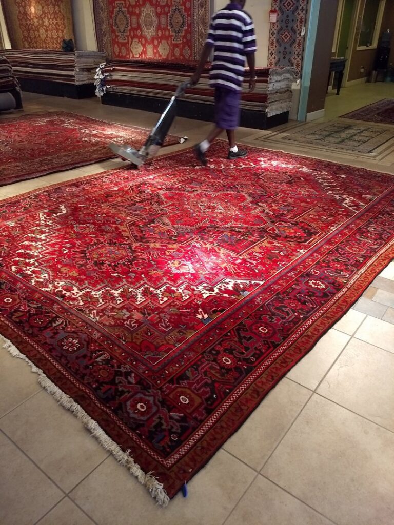 A professional performing rug cleaning on a large oriental rug at Pars Rugs Savannah, GA.