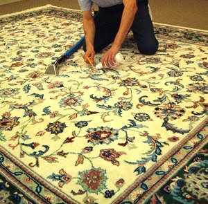 A professional cleaning an ornate area rug by hand, applying solution, by Xtreme Klene Carpet & Upholstery Cleaning in Montgomery, AL.