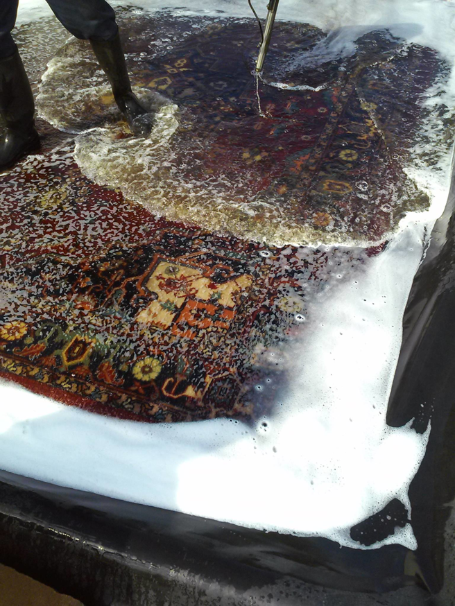 A professional rug washing in progress, with water and soap thoroughly cleaning a patterned rug at Rub A Dub Rug in Las Vegas, NV.