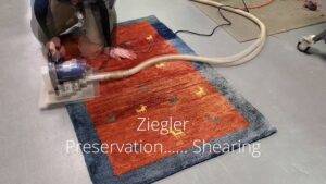 A professional performing shearing on an area rug at Ziegler Preservation Cleaning in Danbury, CT