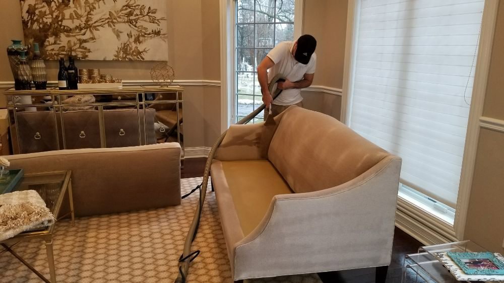 A professional technician cleaning a light-colored sofa upholstery at a client's home by Personal Touch Carpet Cleaning in Chicago, IL.