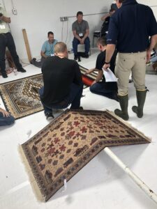 Professionals inspecting and discussing rugs during a training session at the Association of Rug Care Specialists in Salem, OR